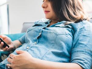 Pregnant woman checking information on smartphone regarding her pregnancy.