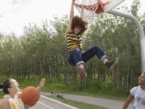 Playful teenage girls playing basketball at park basketball court