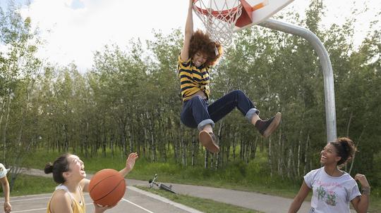 Playful teenage girls playing basketball at park basketball court