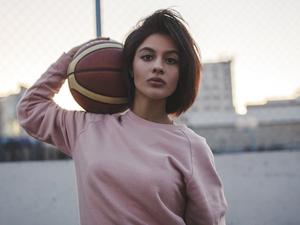 Portrait of young woman holding basketball outdoors