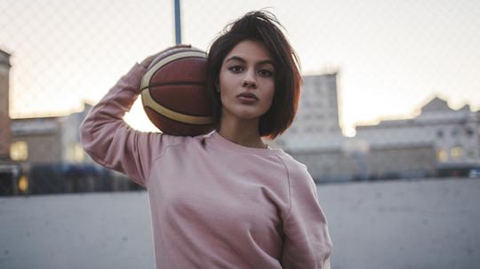 Portrait of young woman holding basketball outdoors