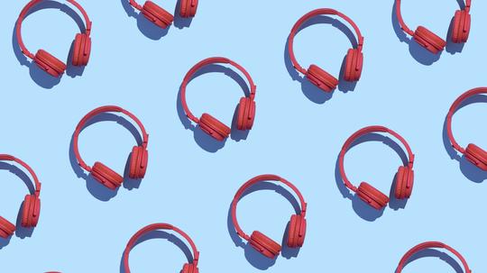 Collection of red wireless headphones on light blue background, 3D Rendering