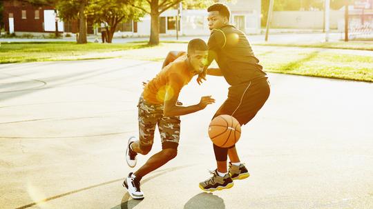 Basketball player dribbling ball past defender