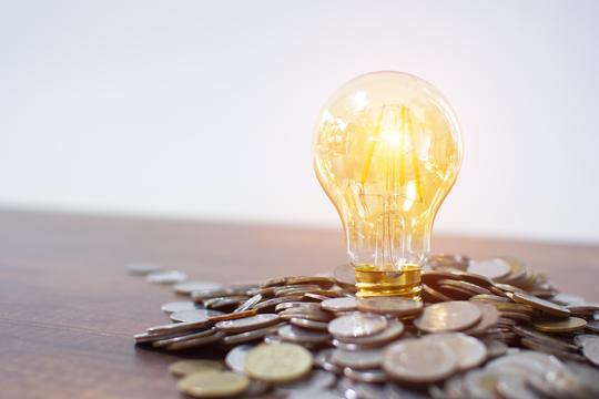 Light bulb and pile of coins with copy space