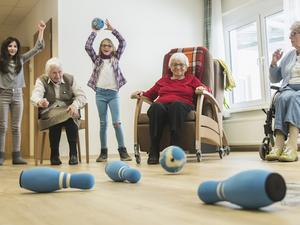 Girls playing bowling with senior women in rest home