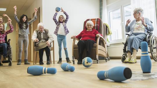 Girls playing bowling with senior women in rest home