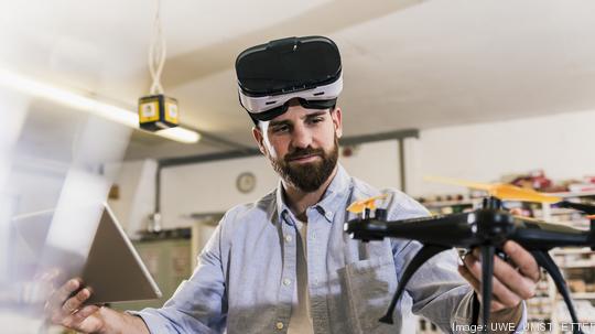 Man wearing VR glasses holding drone and tablet