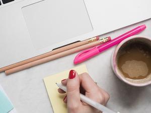 Woman writing on notepad at desk