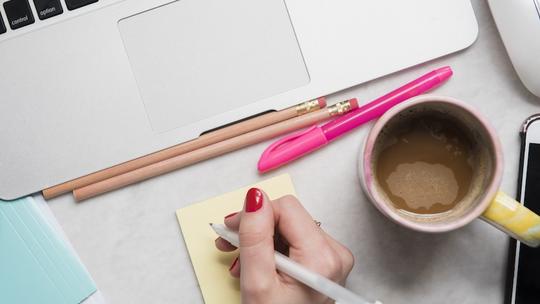 Woman writing on notepad at desk