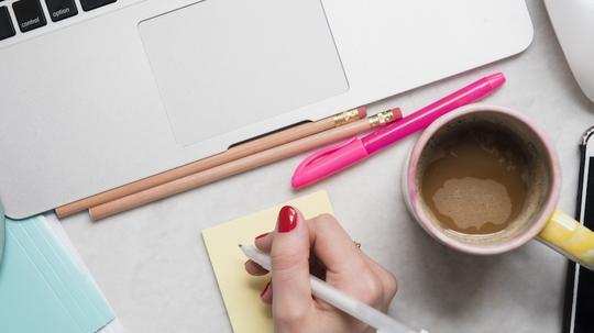 Woman writing on notepad at desk