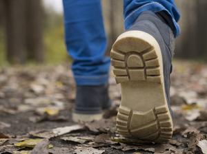 Sole of shoe of Caucasian boy walking on autumn leaves