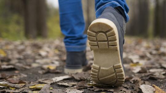 Sole of shoe of Caucasian boy walking on autumn leaves