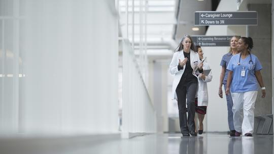 Female doctors discussing while walking in hospital corridor