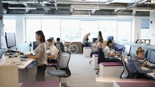 Creative business people working at computers in open plan office