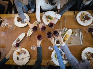 View from above business people toasting red wine glasses at restaurant table