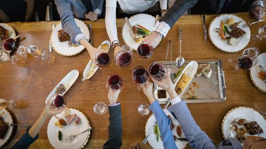 View from above business people toasting red wine glasses at restaurant table