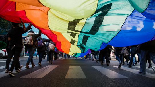 People Walking With Rainbow Flag During Pride Parade