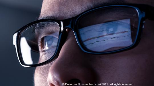 the abstract image of the businessman wear a glasses looking at the stock trading chart on the computer screen. the concept of business, technology, trading, information and internet of things.