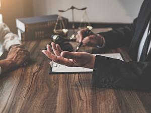 Midsection Of Judge And Client Sitting At Table In Office