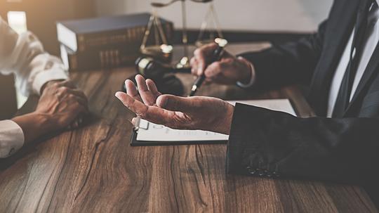 Midsection Of Judge And Client Sitting At Table In Office