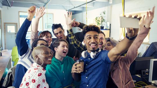 Enthusiastic creative business team taking selfie in office