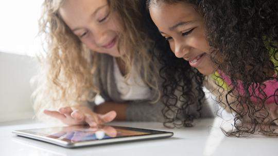 Fabulingua - Smiling girls using digital tablet