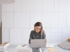 Young female entrepreneur using laptop at desk in workshop