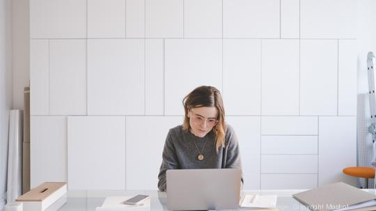 Young female entrepreneur using laptop at desk in workshop