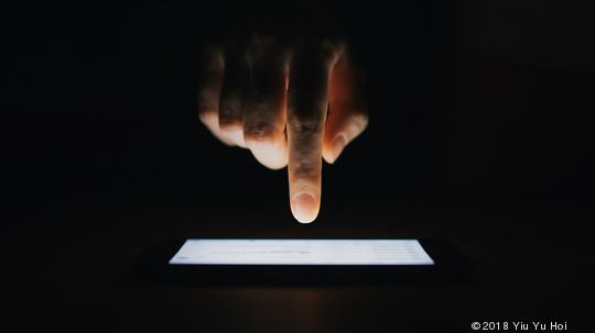 Close up of woman's hand checking emails on smartphone  against black background