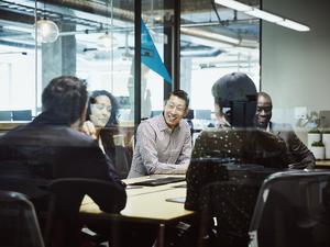 Smiling businessman leading client meeting in office conference room