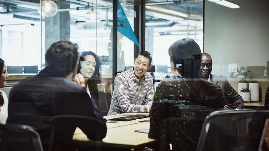 Smiling businessman leading client meeting in office conference room