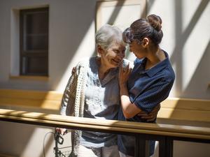 Nurse embracing senior woman in retirement home