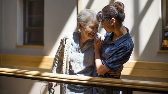 Nurse embracing senior woman in retirement home