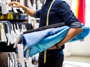 Fashion designer picking the fabric rolls from the rack