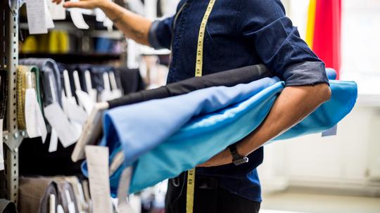 Fashion designer picking the fabric rolls from the rack