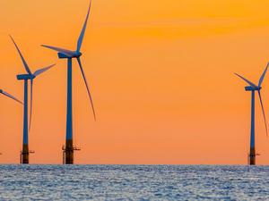 Offshore wind farm energy turbines at dawn. Surreal but natural sunrise at sea.