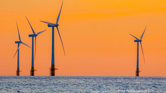 Offshore wind farm energy turbines at dawn. Surreal but natural sunrise at sea.