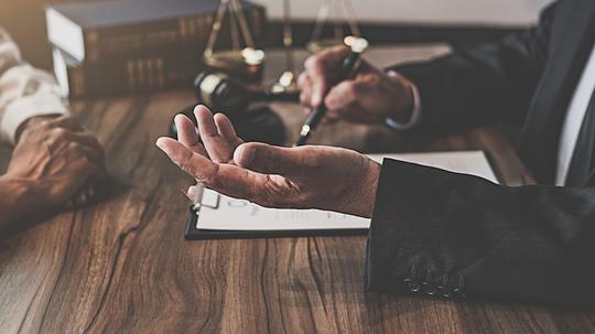 Midsection Of Judge And Client Sitting At Table In Office