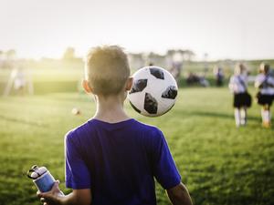 11 year old boy juggling soccer ball while walking off soccer field