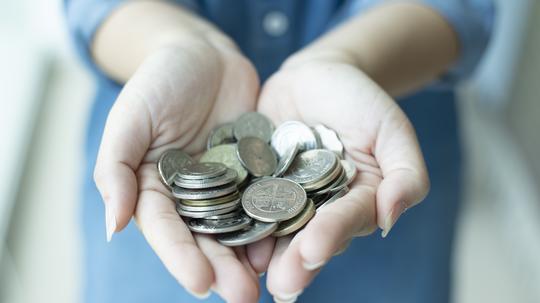 Woman is hand on coins as for saving money.