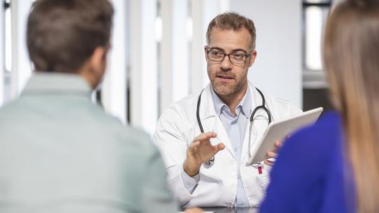 Doctor talking to couple in medical practice