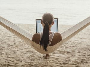 Rear view of woman using laptop computer while relaxing on hammock