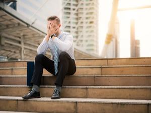 Young business man crying abandoned lost in depression sitting on ground street concrete stairs suffering emotional pain, sadness, looking sick in grunge lighting