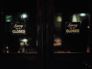 Closed Signs On Wet Glass Door Of Store At Night