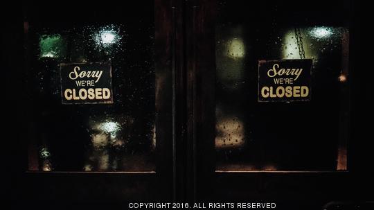 Closed Signs On Wet Glass Door Of Store At Night