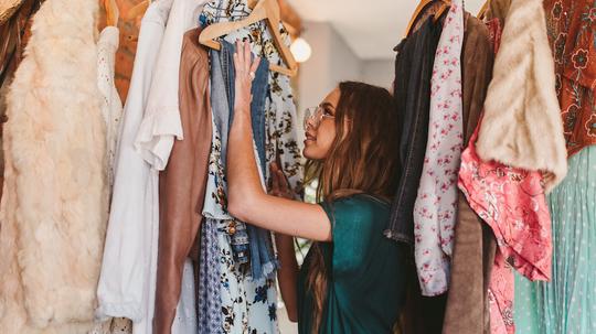 Side View Of Young Woman Hanging Clothes On Rack At Home