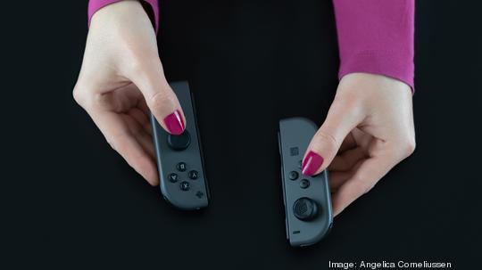 Top View Of Woman Hands With Pink Nail Polish On Fingers Holding Nintendo Switch Gaming