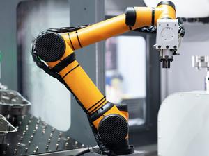 Robot arm 's going to pick parts to CNC machine in the manufacturing factory.