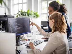 Coworkers discussing computer program in office