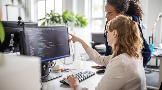 Coworkers discussing computer program in office